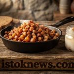 Сковорода с мелкими золотистыми шкварками, рядом стоит стеклянная баночка с прозрачным янтарным жиром.