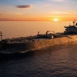 Нефтяной танкер идет по открытому океану в лучах заходящего солнца