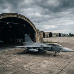 Военный истребитель на бетонированной площадке ангара авиабазы