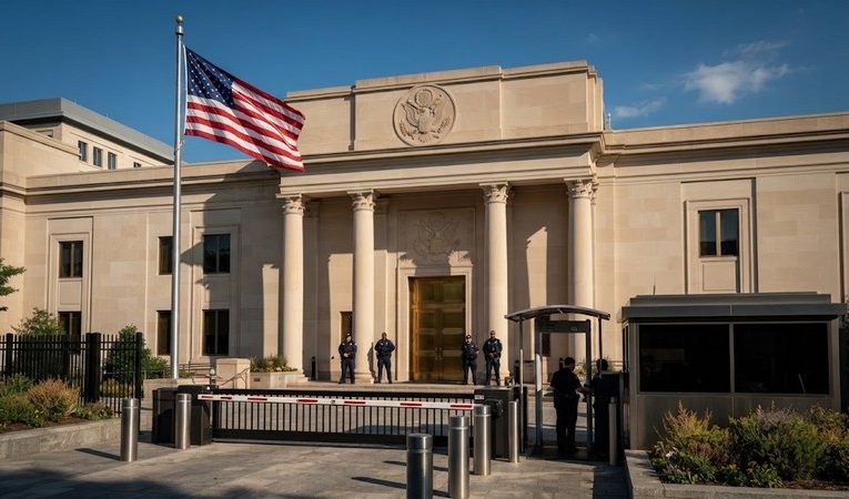 Здание посольства США в Вашингтоне с американским флагом у входа днем
