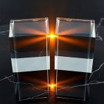Два одинаковых прозрачных стеклянных куба, соприкасающихся углами на темной полированной поверхности.
