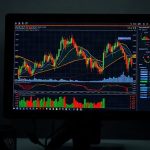 Современные светящиеся цифровые графики торговли криптовалютами и финансовой аналитики на экране темного компьютерного монитора в профессиональном офисе