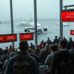 Очереди пассажиров в зале вылета аэропорта на фоне табло с отменами рейсов из-за транспортного коллапса в США